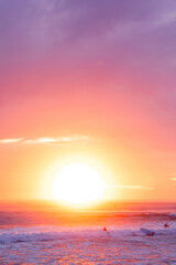 Naklejka na ściany i meble Sunlit sky ocean sunrise with surfers