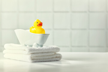 A miniature bubble bath, yellow rubber duck and white towels on bathroom countertop, children bath...