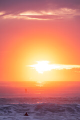 Obraz premium Sunlit sky ocean sunrise with surfers