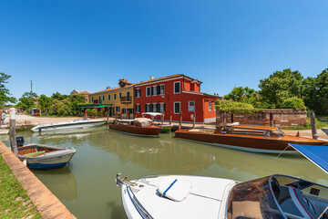 Port of Torcello island with many speed boats and two traditional water taxis made of wood moored....