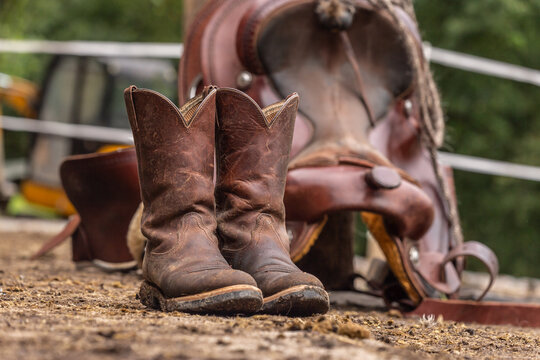 Ranch life scenery: muddy western boots in front of a western saddle.  Cowboy boots. Muddy working boots Stock Photo | Adobe Stock