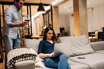 young woman mother working from home at the couch with a laptop pc with her little baby