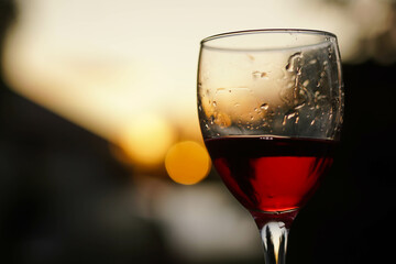 Glass of red wine on the vineyard at sunset, close up