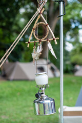 Vintage hanging lantern and dreamcatcher with a tent in the background in campsite area at the forest