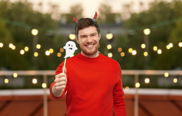 holiday and people concept - happy smiling man in halloween costume of devil with party accessory...