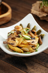 Roasted potatoes with mushrooms and pickles on the wooden background