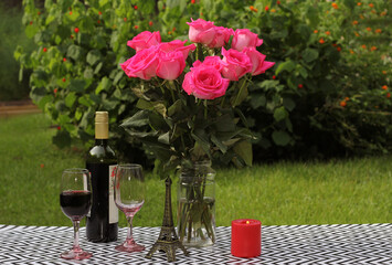Bouquet of Roses on Outdoor Table With Wine and Candle in Garden