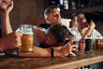 Side view of friends with beer. People in casual clothes sitting in the pub