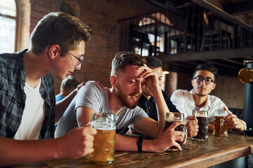 Side view of friends with beer. People in casual clothes sitting in the pub