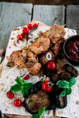 Pork shashlik on pita bread with vegetables close-up