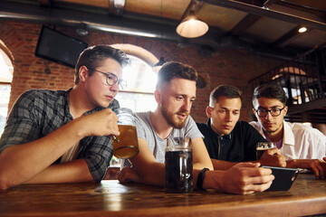 Side view of friends with beer. People in casual clothes sitting in the pub