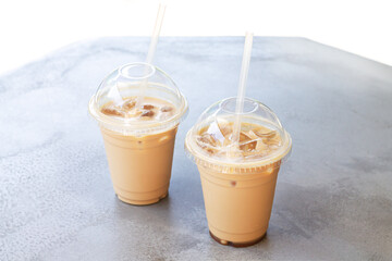 Iced coffee or latte in take away plastic cup on street cafe stone table