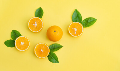 Oranges are laid out with leaves on a yellow background
