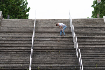 Exhausted man going up on stairs just before reaching the top. Hard way to success and achieving goals concept