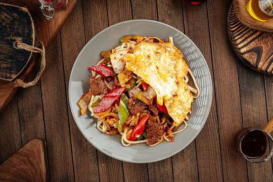 Asian uyghur dish guiru lagman noodles with omelette on a wooden background