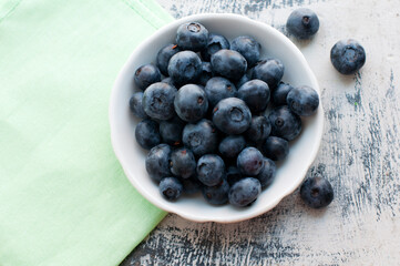 Blueberries on a white plate on a white wooden background. Top view