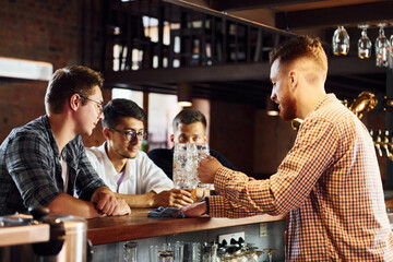 Cheerful young people in casual clothes sitting in the pub