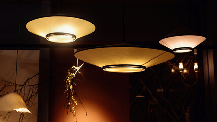A group of fashionable modern illuminated chandeliers in a dark room. Luxury hanging ceiling lights