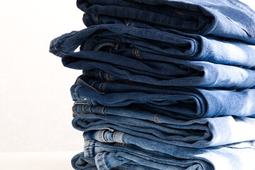 a pile of blue jeans on a light background. Sunlight. Close up