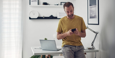 Man using smartphone at home while making pause from work.