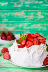 Pavlov's cake with strawberries and cream on a rustic background
