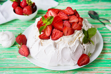 Pavlov's cake with strawberries and cream on a rustic background