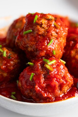 Close up of meatballs with tomato sauce into the white ceramic ball on the table. Copy space