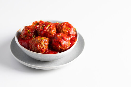 Meatballs with tomato sauce into the white ceramic ball on the table. Copy space