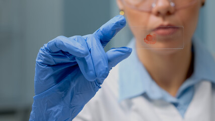 Close up of hand holding glass tray with blood for test experiment in science laboratory. Doctor with gloves analyzing dna sample on microbiology tool for professional medical diagnosis