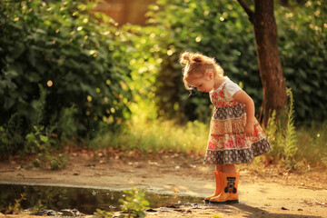 little girl near the puddle in yellow rubber boots