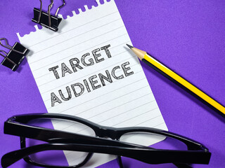 Business concept.Text TARGET AUDIENCE writing on notepaper with glasses,paper clips and pencil on...