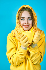 young woman with tea mug in her hands. model in yellow clothes. blue background. autumn concept