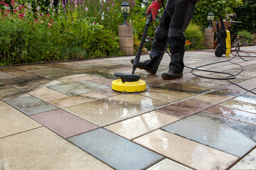 Cleaning stone slabs on patio with the high-pressure cleaner. Person worker cleaning the outdoors...