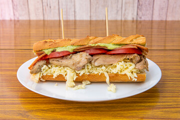 Wild chicken sandwich with grated fresh cheese, tomato slices, fried bacon and avocado sauce
