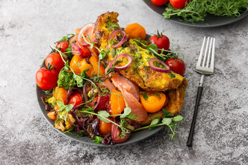 Omelet with stewed vegetables and salmon, tomatoes with onions, broccoli and red fish with pea microgreens, delicious hearty breakfast