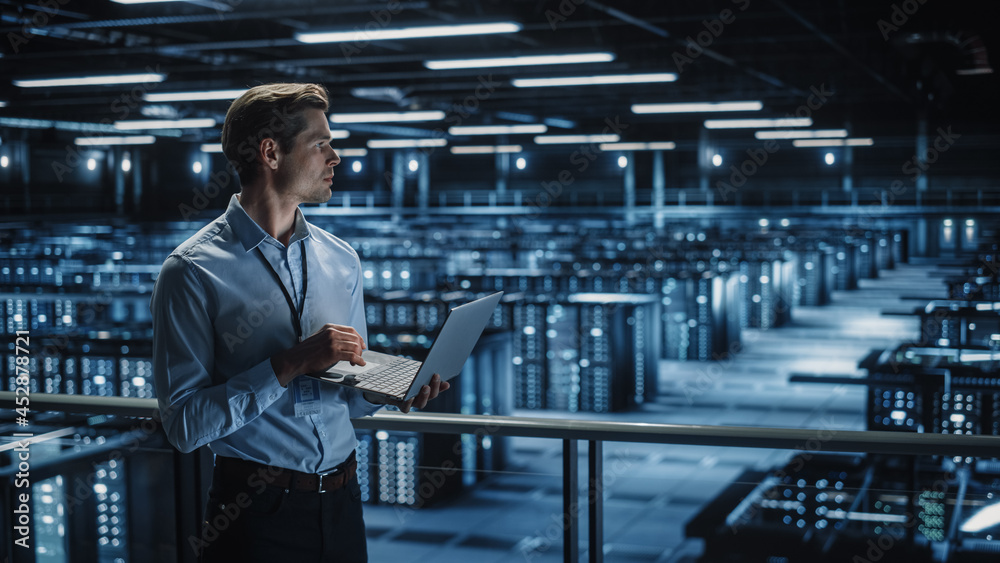 Fototapete Data Center Specialist Engineer Using Laptop Computer. Server Farm Cloud Computing Facility with Male Maintenance Administrator Working. Data Protection Network for Cyber Security.