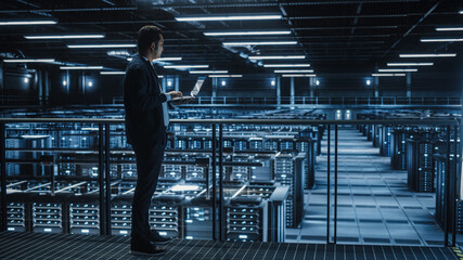 Data Center Male Administrator Using Laptop Computer. Cloud Computing Facility Maintenance...