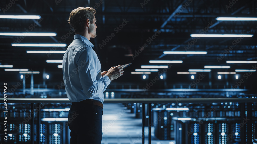 Fototapete Handsome Smiling IT Specialist Using Tablet Computer in Data Center. Succesful Businessman and e-Business Entrepreneur Overlooking Server Farm Cloud Computing Facility.
