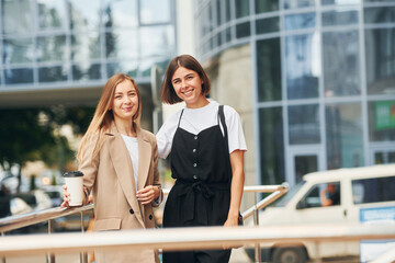 Standing together. Women in formal wear is outdoors in the city