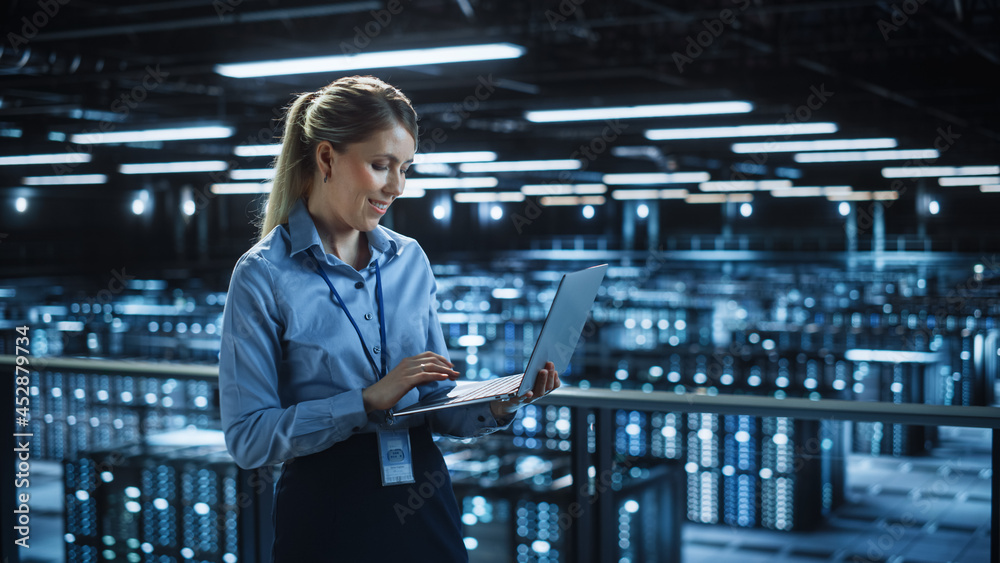 Poster Portrait of IT Specialist Using Laptop in Data Center. Big Server Farm Cloud Computing Facility with Female System Administrator Monitoring. Cyber Security, Network Protection Services.