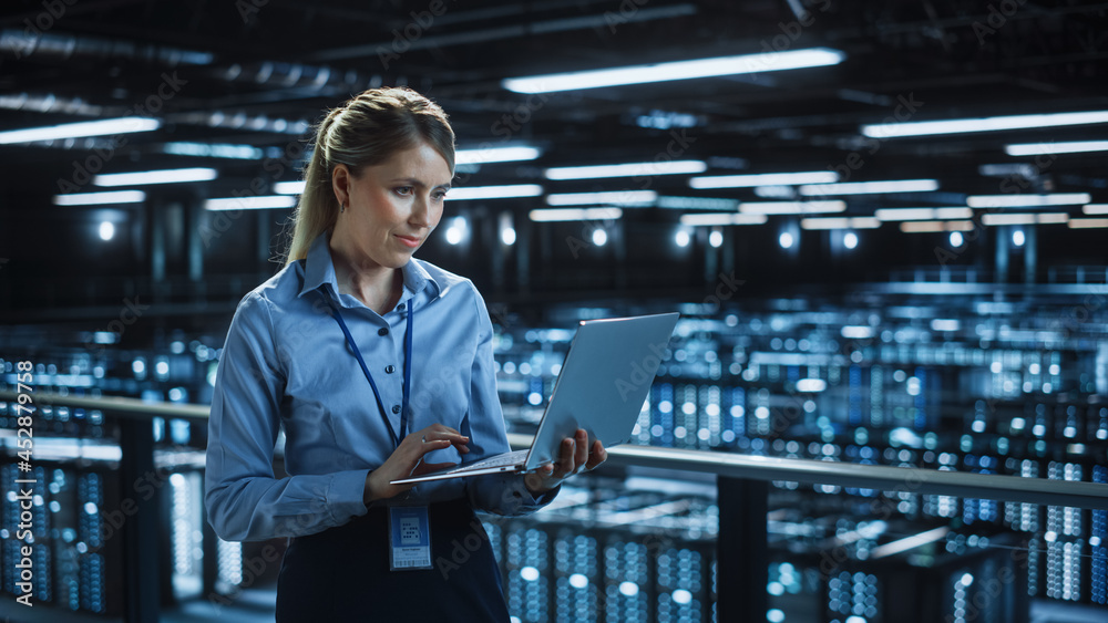 Poster Portrait of IT Specialist Using Laptop in Data Center. Big Server Farm Cloud Computing Facility with Female System Administrator Monitoring. Cyber Security, Network Protection Services.