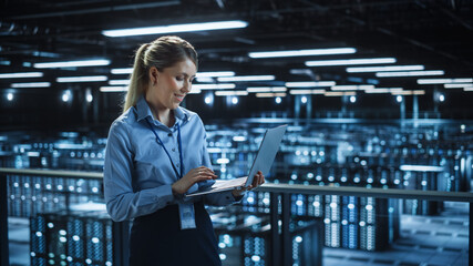 Portrait of IT Specialist Using Laptop in Data Center. Big Server Farm Cloud Computing Facility...
