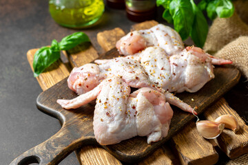 Raw chicken wings on a wooden board on a dark culinary background closeup