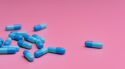 Obraz na płótnie Canvas Blue antibiotic capsule pills on pink background. Online pharmacy banner. Group of antibiotic capsule pills. Pharmaceutical industry. Antibiotic drug resistance. Antimicrobial drug. Prescription drug.