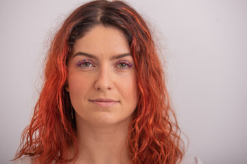Naklejka premium Portrait of caucasian red-haired woman with colored eyelashes on white background.