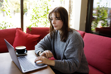 Young woman having Zoom video call via a computer in the home office. Stay at home and work from home concept during Coronavirus pandemic.