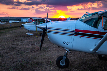 Fototapeta na wymiar Close-up small private aircrafts parked at the airfield at picturesque sunset