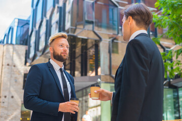 Confident businessman and his colleague in front of modern office building. Financial investors are talking outdoor. Banking and business.