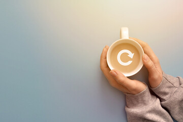 A cup of coffee in the hand of a person with a reboot icon. Coffee break symbol