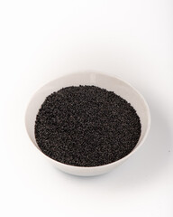 Black sesame seeds in a white plate isolated on a white background. High quality photo